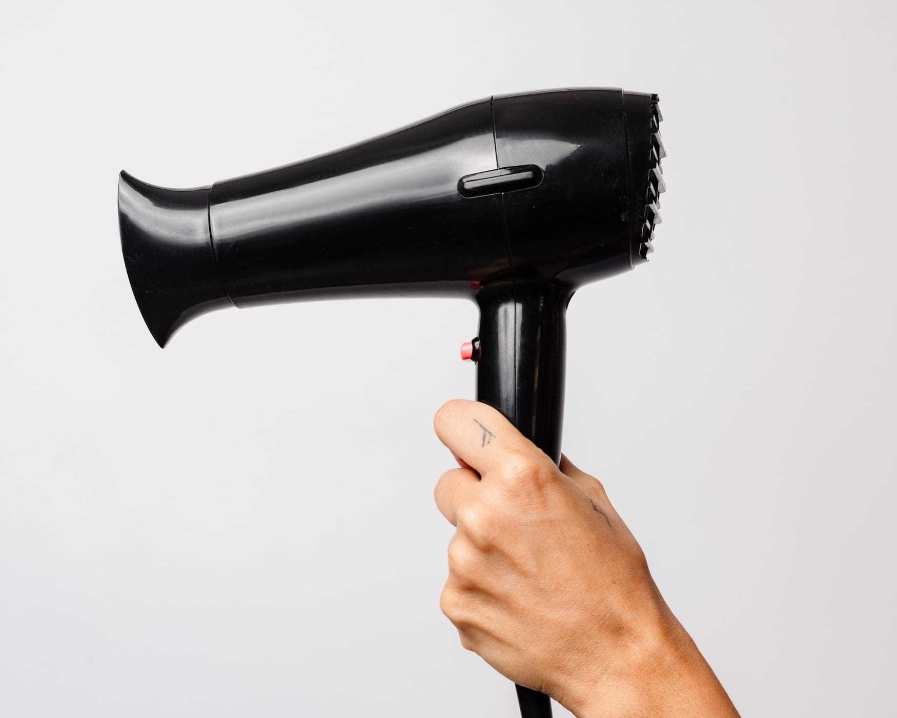 Hand holding a black hair dryer against a plain white background.