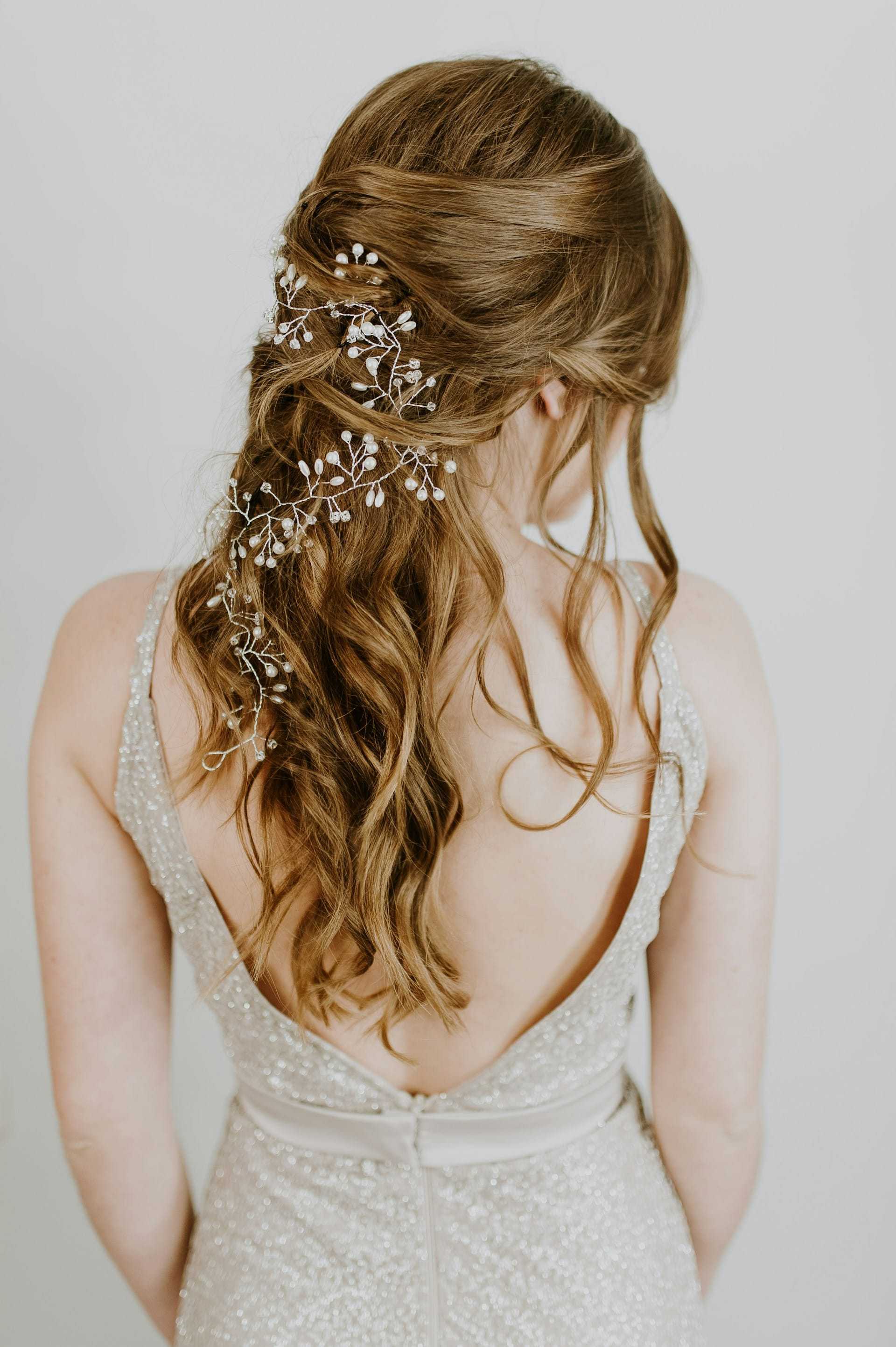 Brunette in sparkling dress with intricate floral hairpiece, back turned.